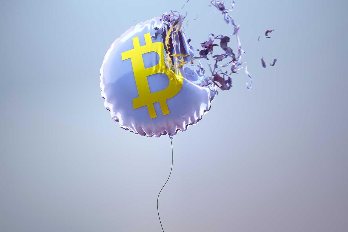 A balloon with a Bitcoin logo getting popped