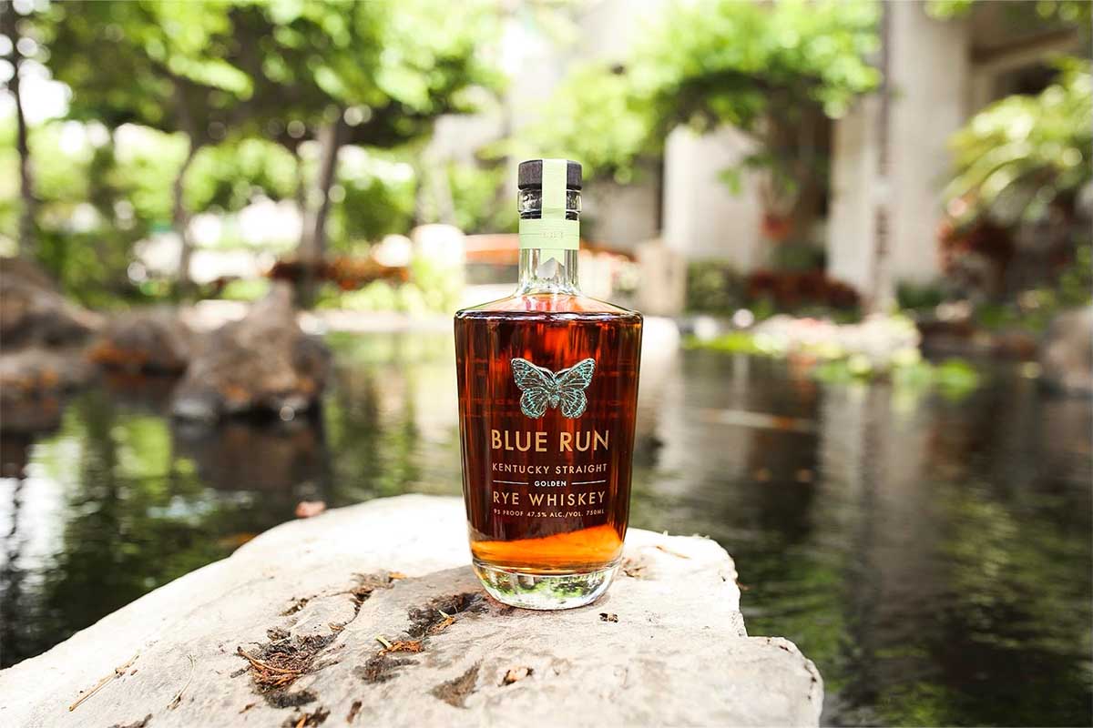 In a forest on a rock, a bottle of Blue Run Golden Rye Whiskey Batch 2, on sale today and probably selling out today.
