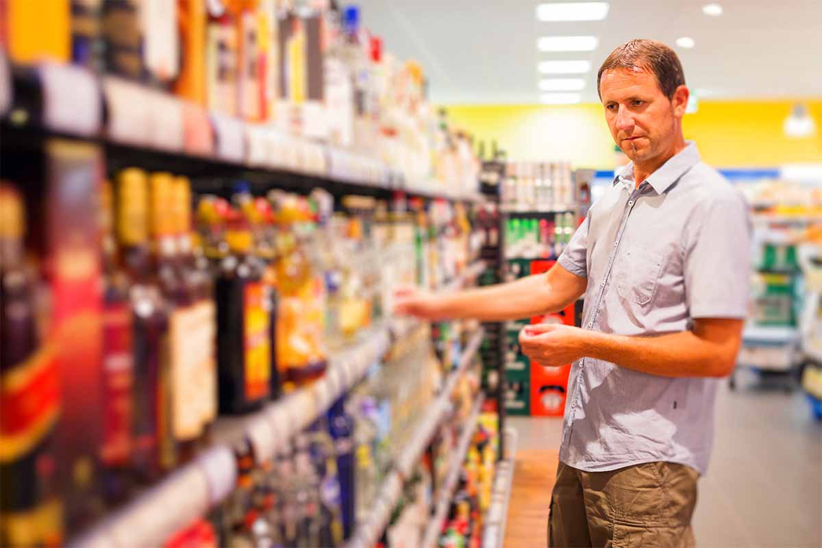 A man shopping for booze at a supermarket. Prices for whiskey have actually decreased over the past three years.