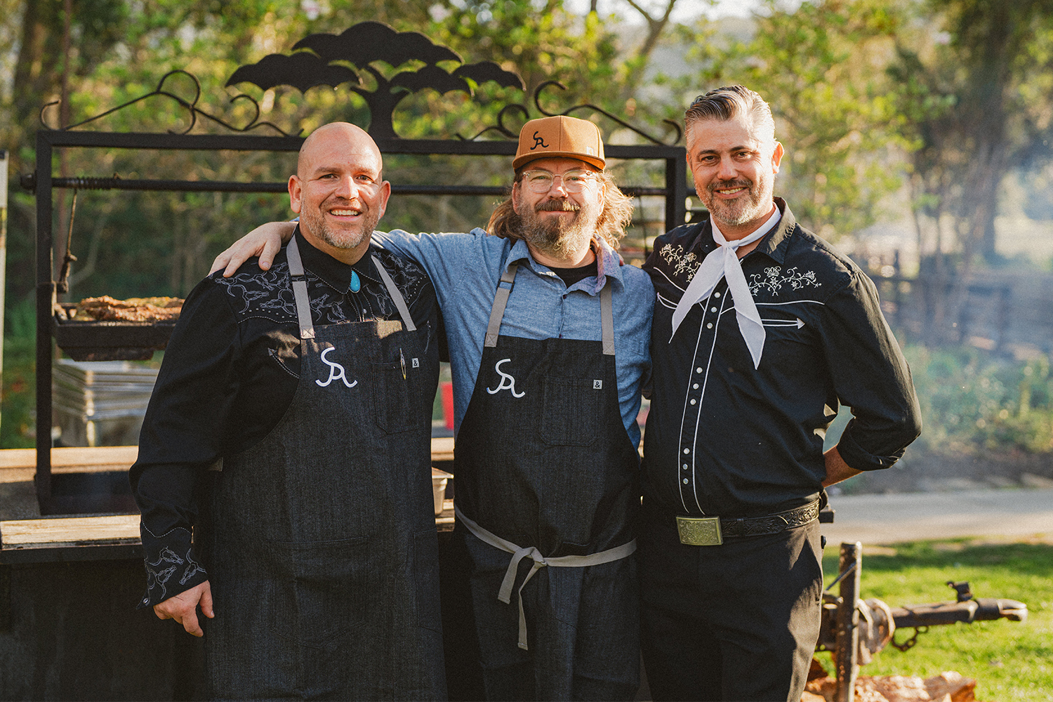 Chef Neal Fraser, pictured in the center with a hat, has his arms around two people at his annual Beefsteak event in 2022