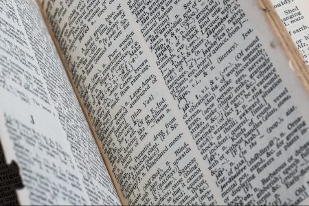 A very old dictionary with torn pages against a white background.