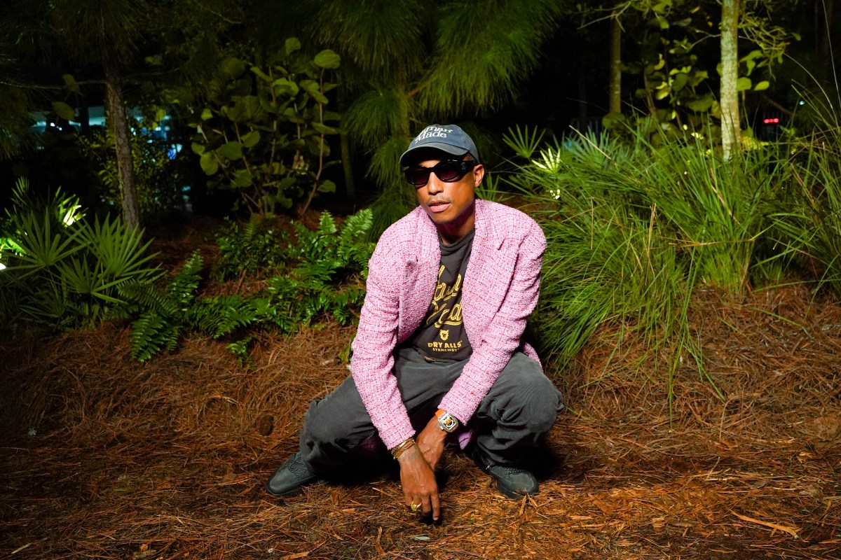 Pharrell crouching in a woodland setting for a photo shoot.