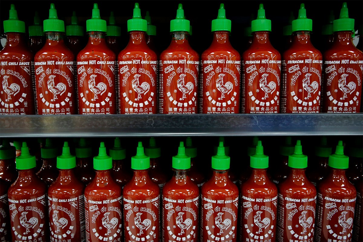 Dozens of red and green bottles of Sriracha hot sauce from Huy Fong Foods on store shelves