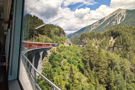A train going around a curve over a bridge in Switzerland