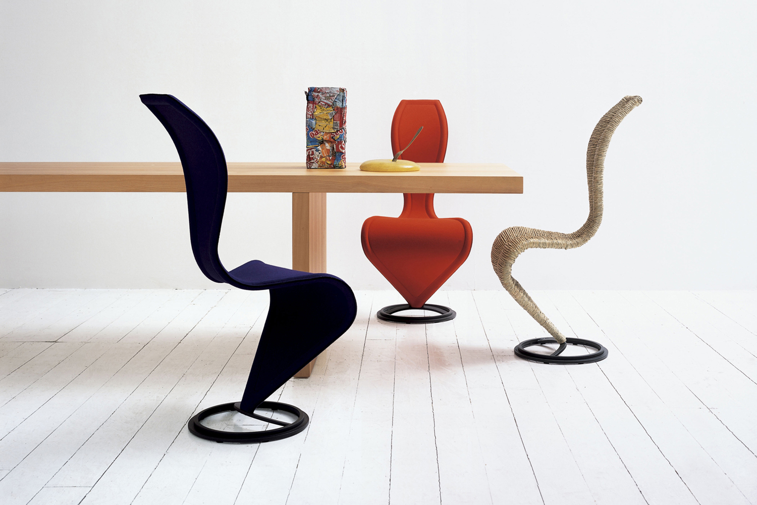 Three versions of the Tom Dixon S-Chair sitting around a table
