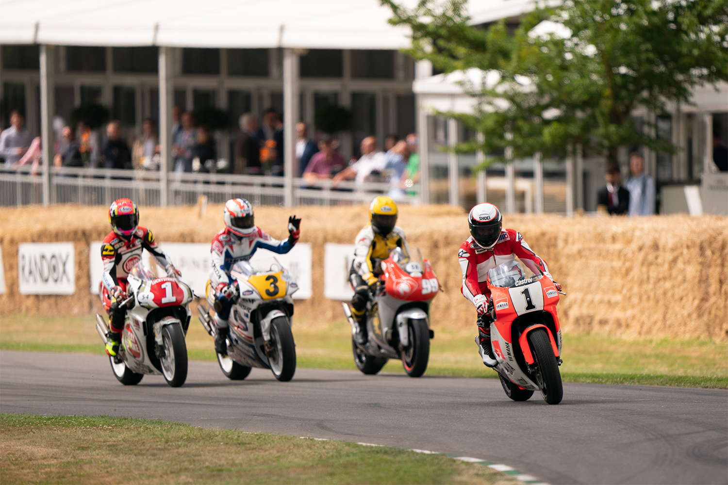 Wayne Rainey, who was paralyzed in 1993 during the height of his motorcycle racing career, rides at the front of a four-person pack at the 2022 Goodwood Festival of Speed