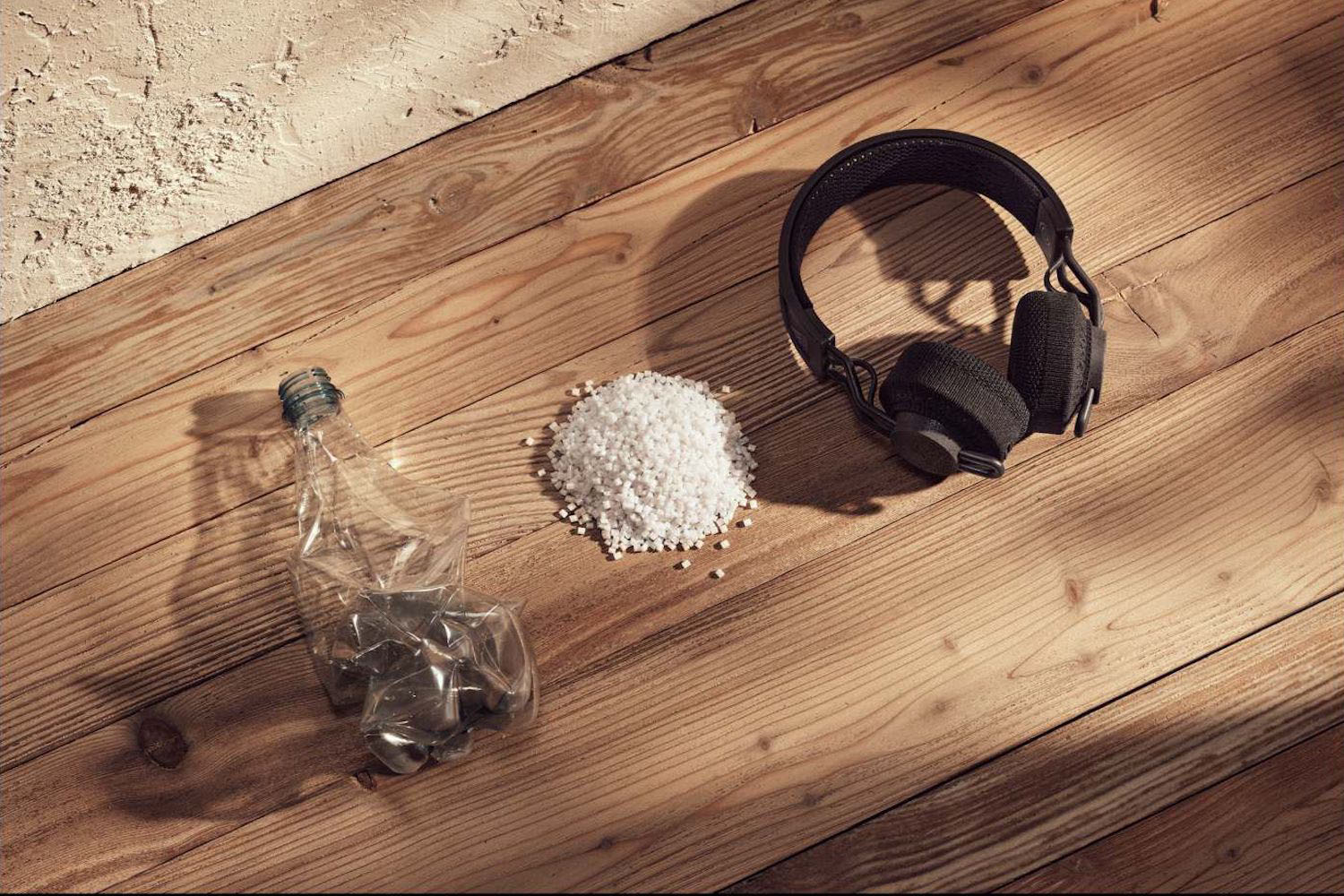 a pair of Adidas headphones next to recycled plastic on a wooden floor