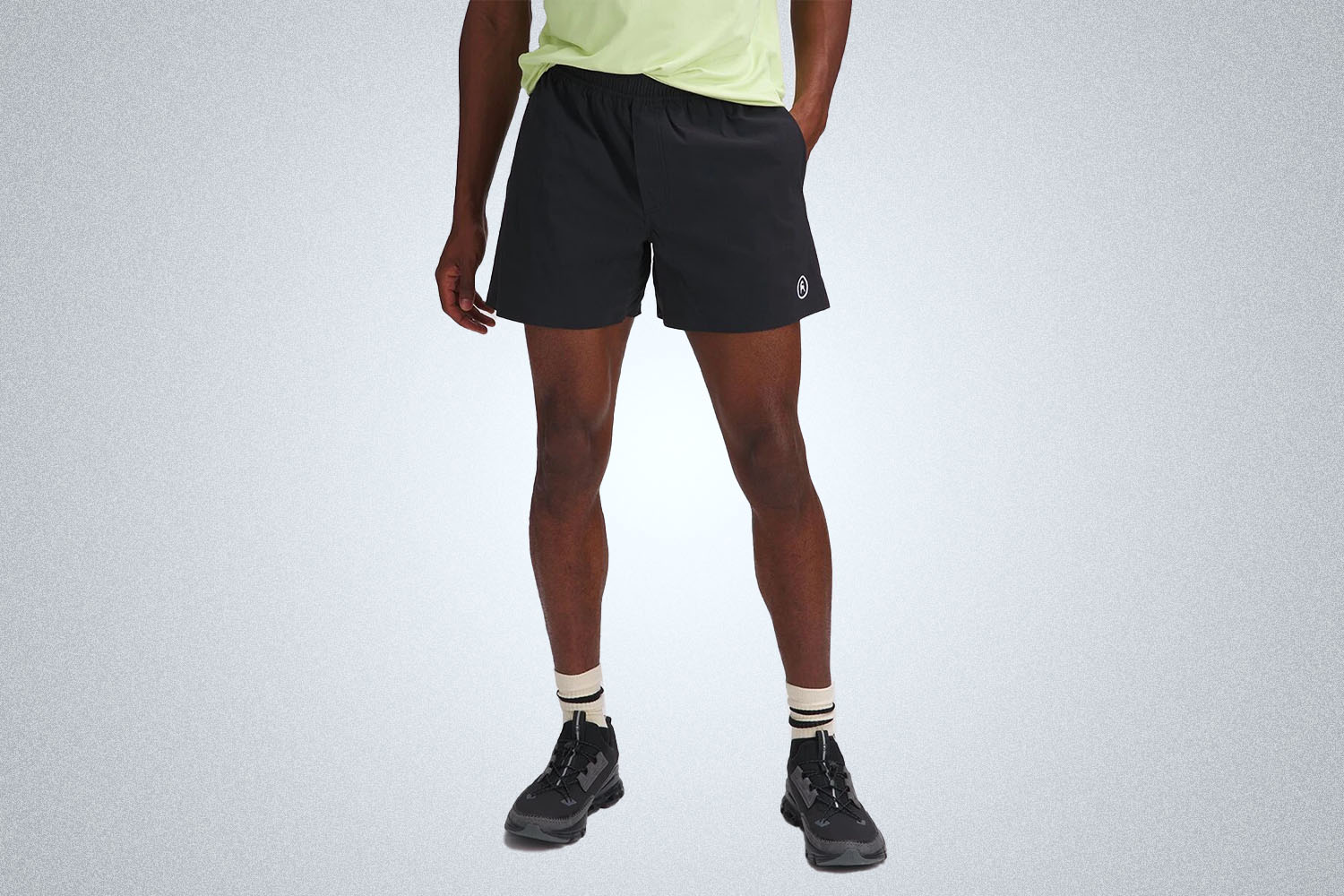 a model in a pair of Backcountry black 5" River Shorts on a grey background