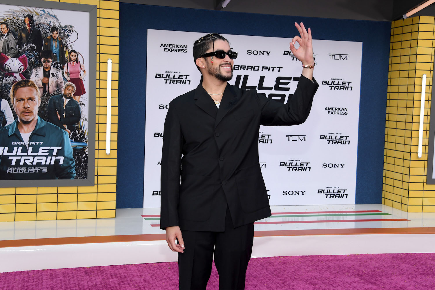 a photo of bad bunny giving the peace sign in a all-black suit