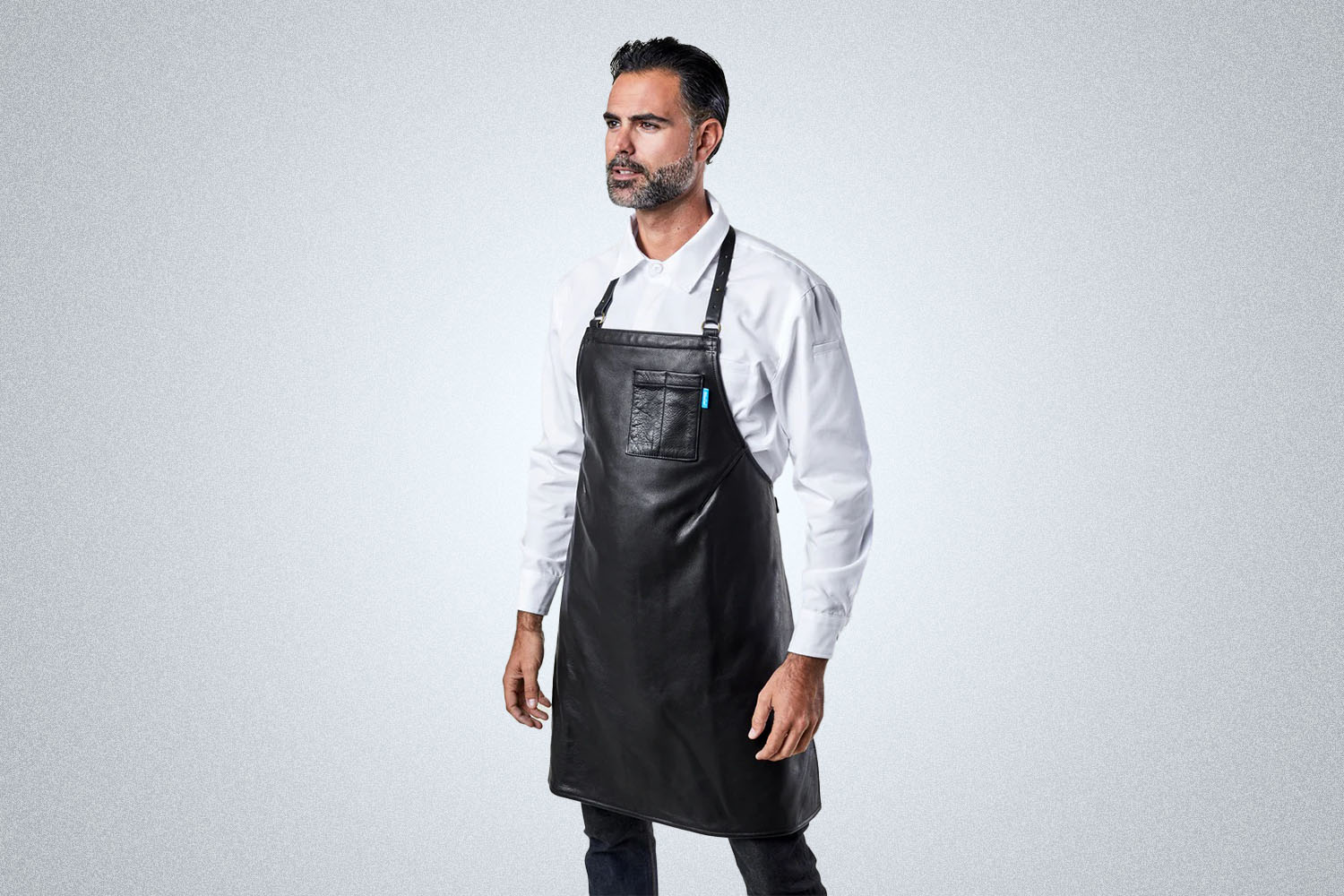 a model in a white shirt and black BlueCut leather apron on a grey background