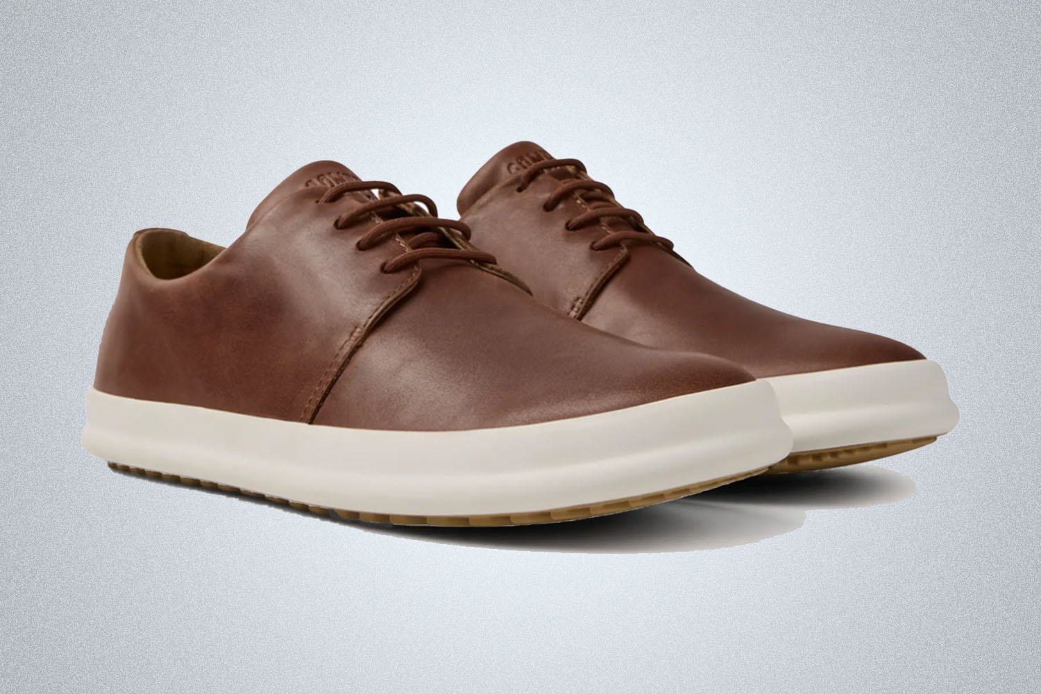 a pair of brown office sneakers from Camper on a grey background