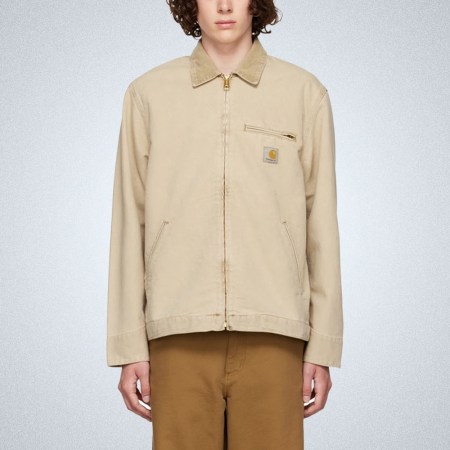 a model in a slightly cropped tan workwear jacket from Carhartt WIP on a grey background