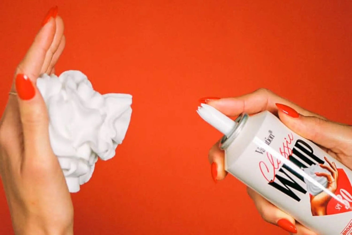 a can of vacation whip sunscreen and a hand with sunscreen on a red background