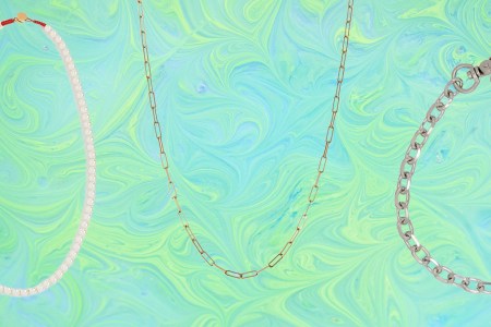 a collage of necklaces and chains on a marbled green and blue background