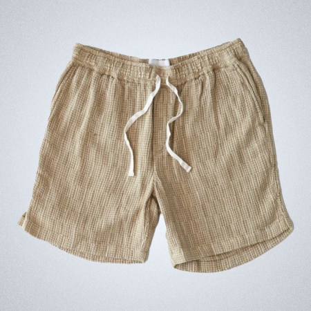 A pair of Corridor's Rainbow Weave drawstring shorts on a grey background
