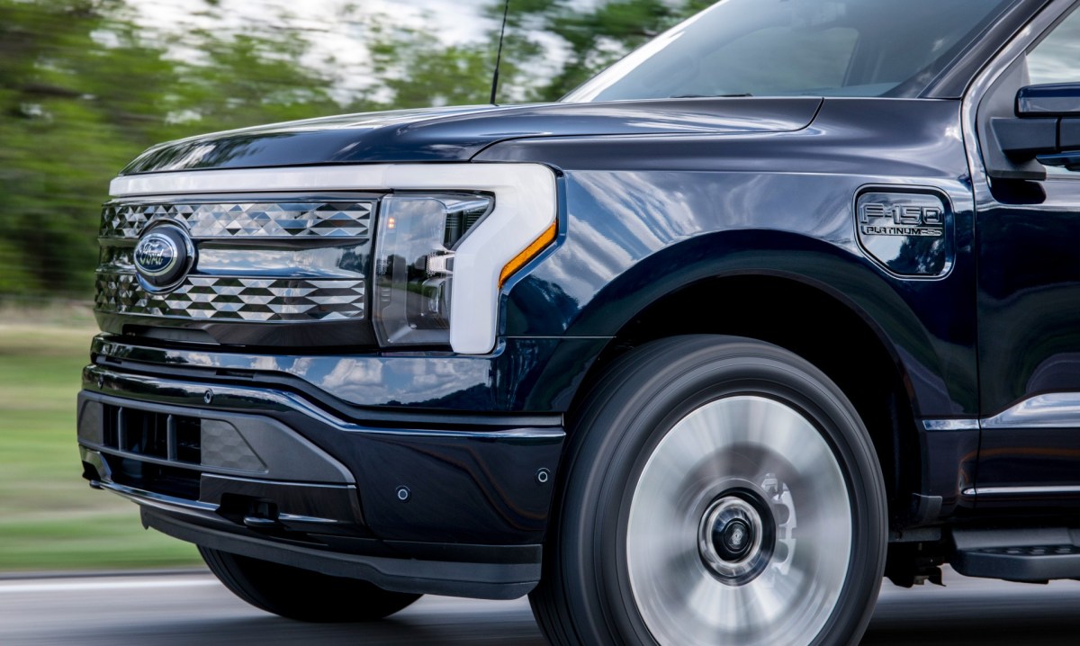 The front end of the Ford F-150 Lightning, the electric pickup truck, as it drives down the road