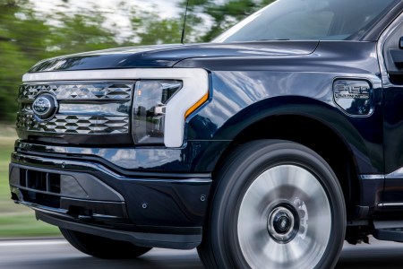 The front end of the Ford F-150 Lightning, the electric pickup truck, as it drives down the road