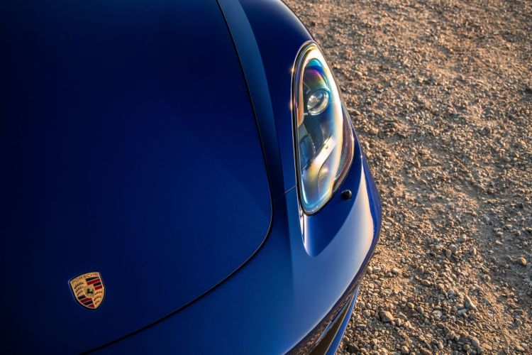 The hood and front left headlight of a blue Porsche Boxster. Porsche is now expected to launch an IPO in September 2022.