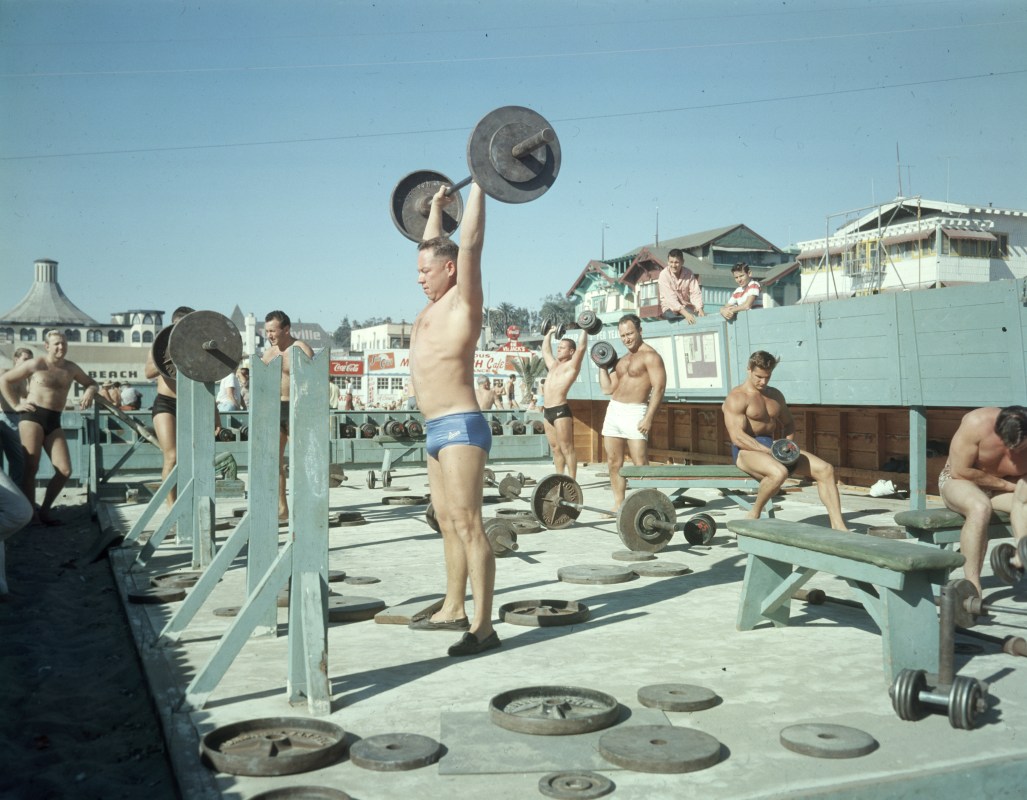 A group of men lifting at Muscle Beach in the 1960s.