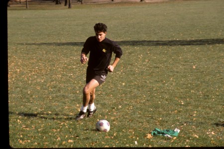 A young man dribbles a soccer ball on a patch of grass in Central Park.