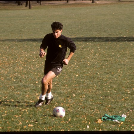 A young man dribbles a soccer ball on a patch of grass in Central Park.