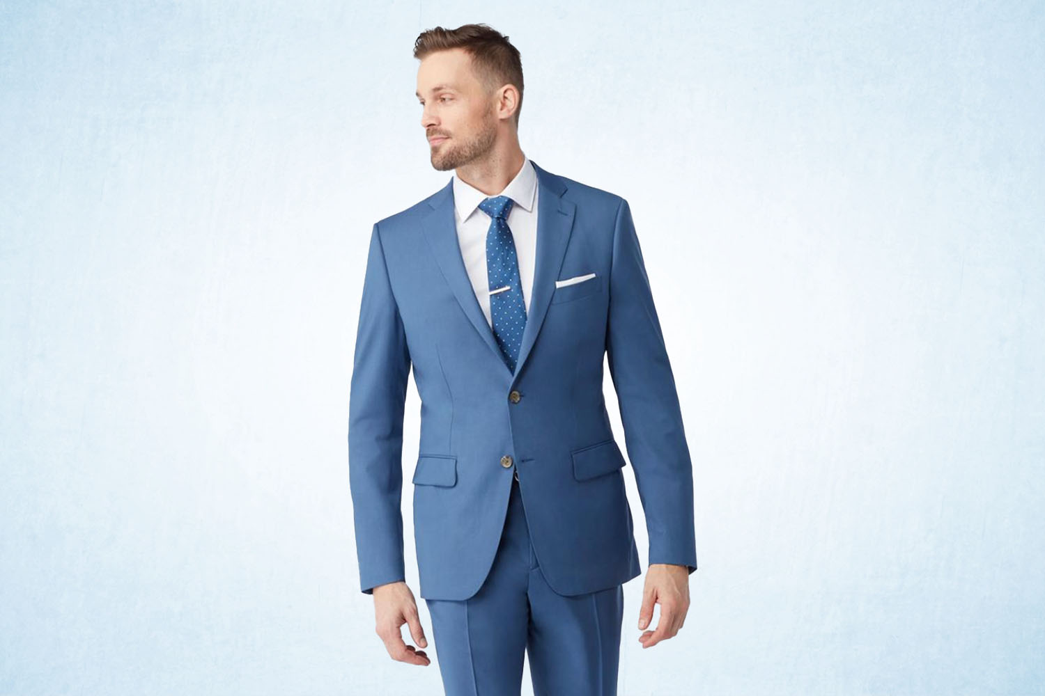 a model in a stone blue double-button suit from Indochino on a ice-blue background