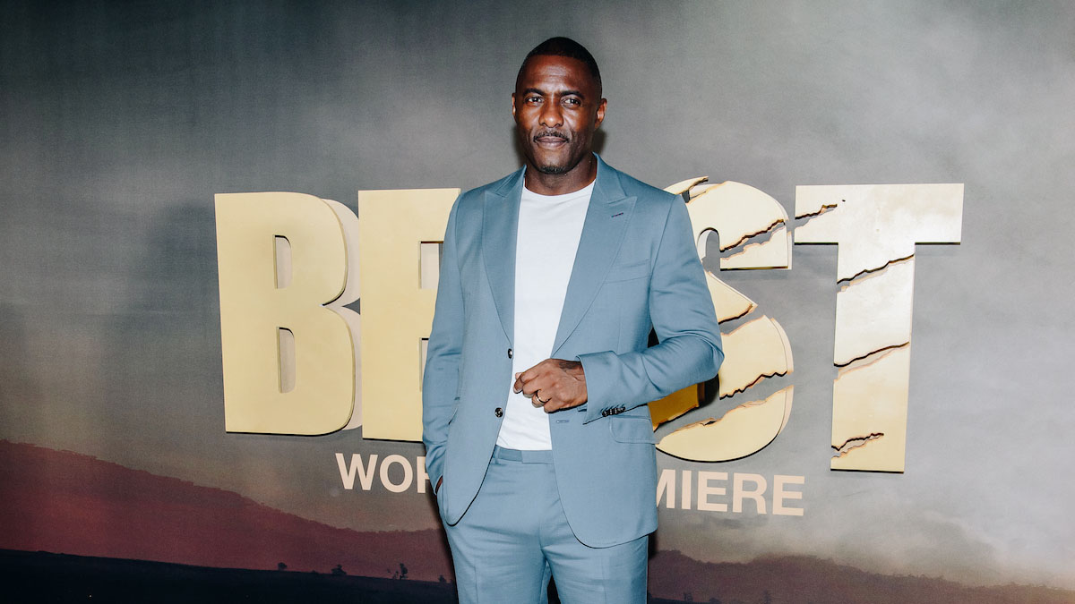 A photograph of actor Idris Elba at the Premier of "Beast" in a light chambray bule suit and white tee shirt