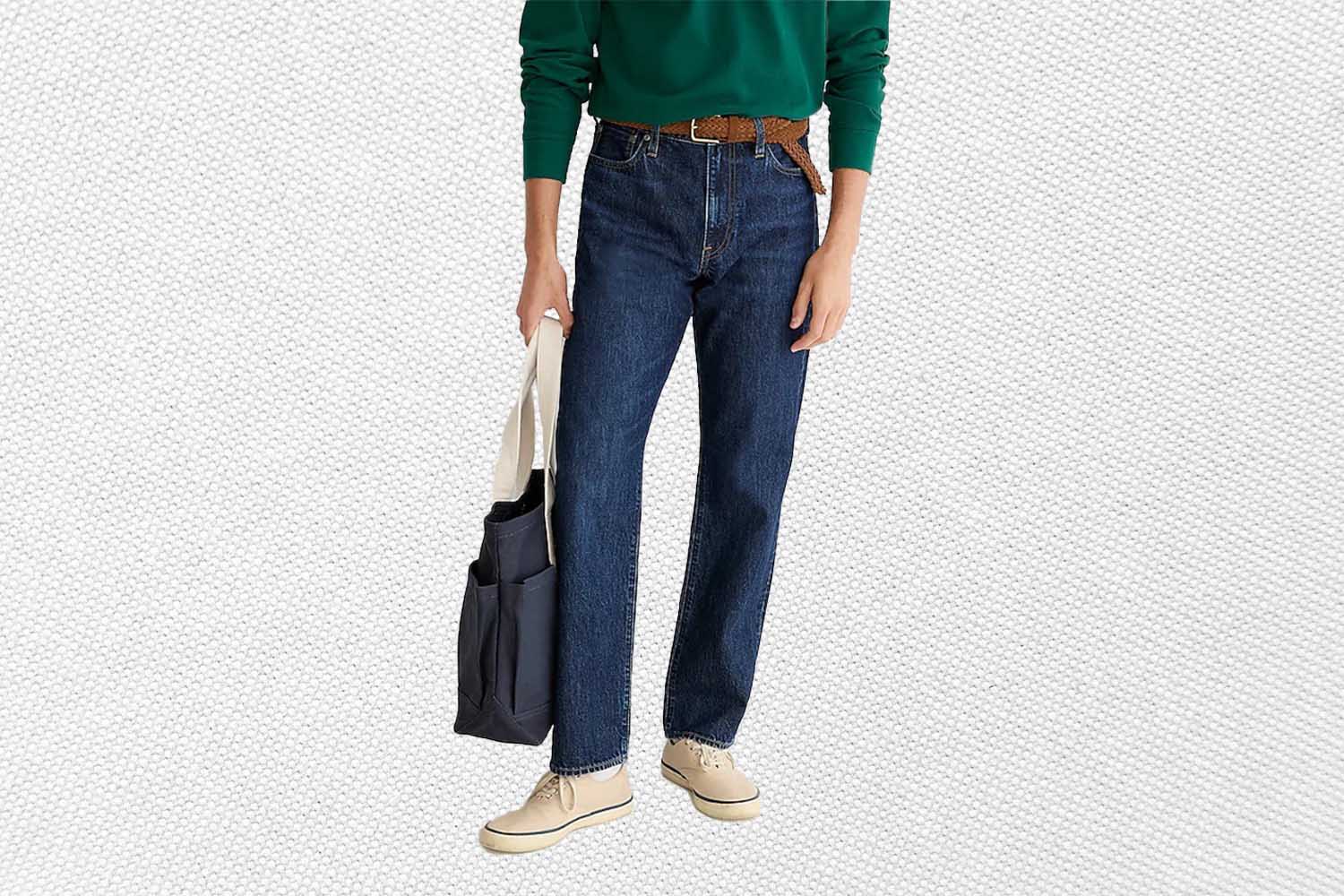 a model in a pair of dark jeans from J.Crew on a grey background