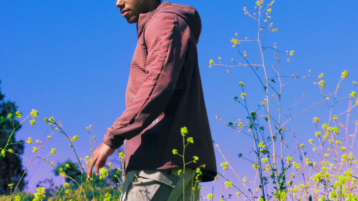 A photograph of a model in Lululemon Hike clothing standing in a grassy field against a blue sky