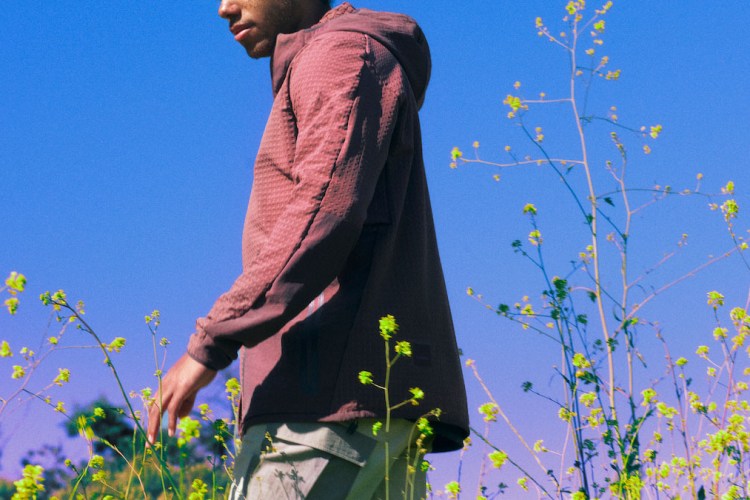 A photograph of a model in Lululemon Hike clothing standing in a grassy field against a blue sky