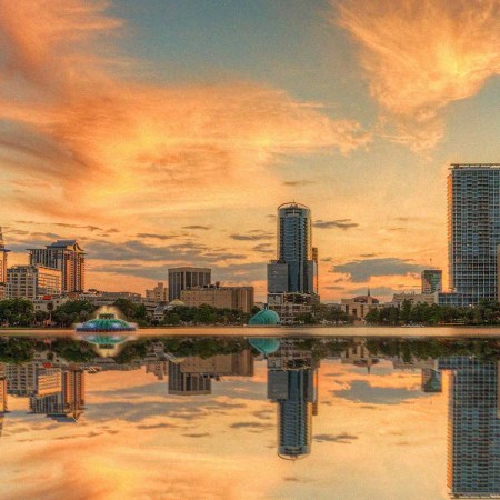 A colorful sunset over Lake Eola and Orlando, Florida with reflections captured off the lake.