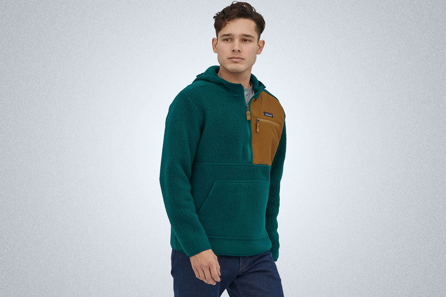 a model in a teal patagonia pull over on a grey background