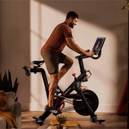 A man at home on a Peloton bike. The fitness brand has started selling some of its products on Amazon, marking a business shift.
