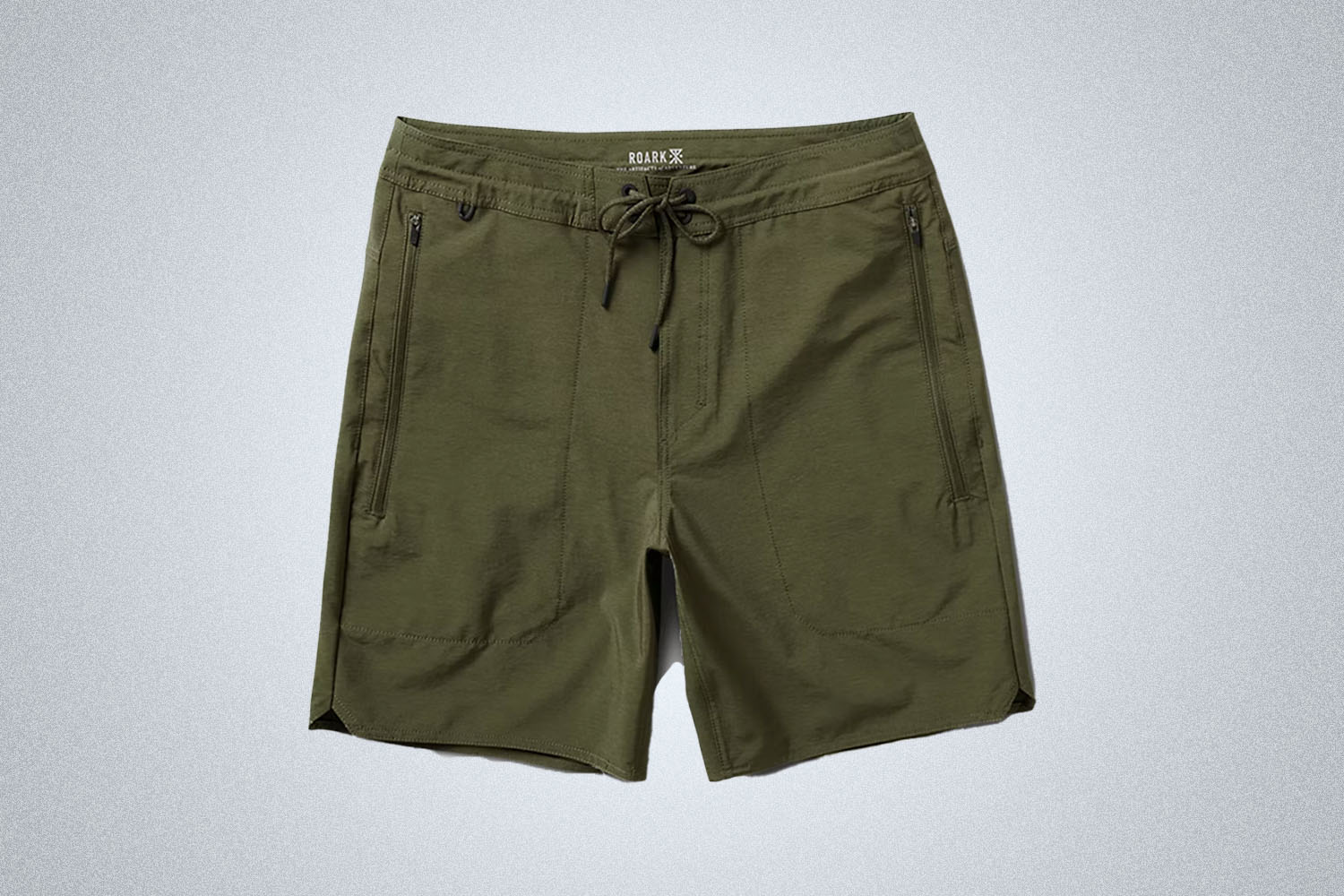 a pair of green technical shorts from Roark on a grey background