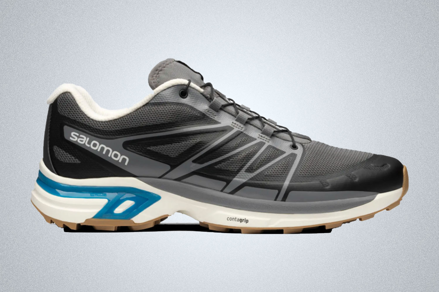 a grey, blue and white Salomon hiking shoe on a grey background