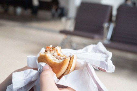 Hands holding an hamburger in an airport departure lounge