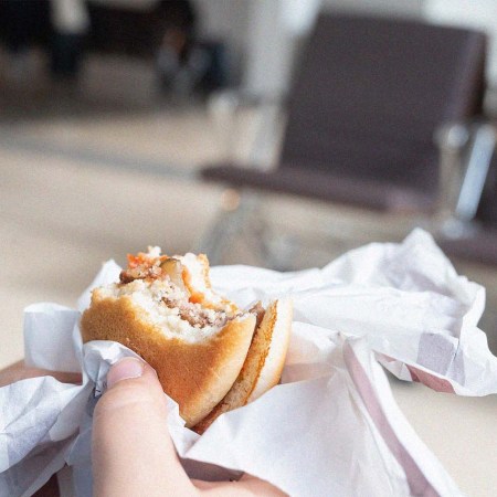 Hands holding an hamburger in an airport departure lounge