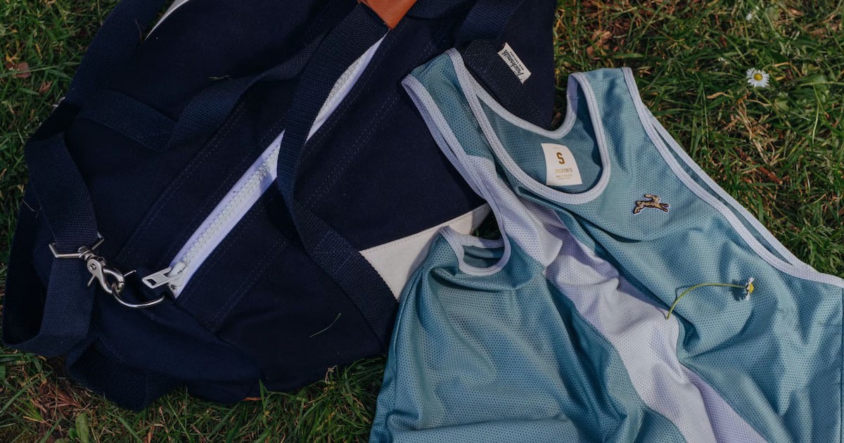 a tracksmith navy bag and blue tank top on grass