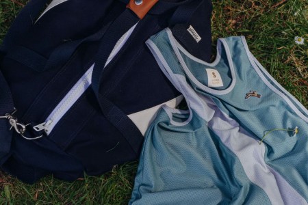 a tracksmith navy bag and blue tank top on grass