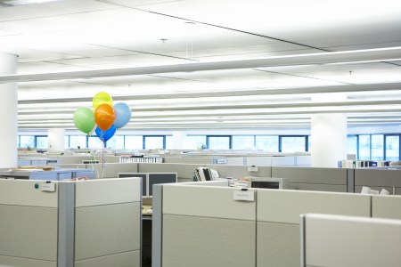 Balloons floating in the middle of a boring office.