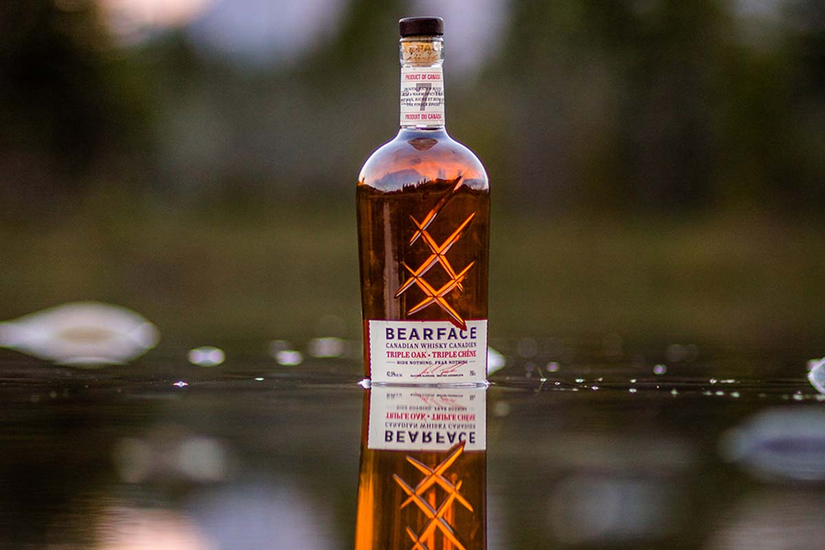 A bottle of Bearface Triple Oak Canadian Whisky in a lake