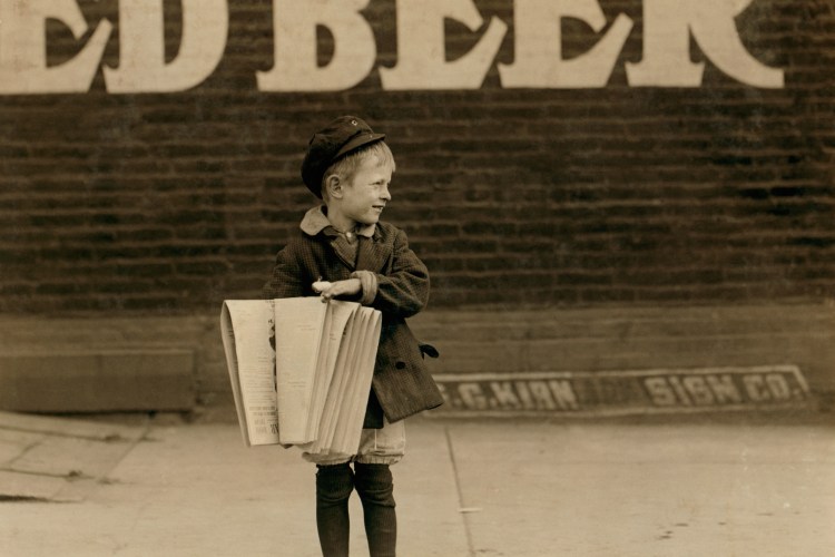 A newsie standing on a street corner in the early 20th century.