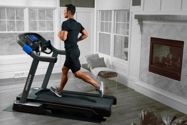 A man running on the Horizon Fitness 7.0 AT Studio Series Treadmill in a house