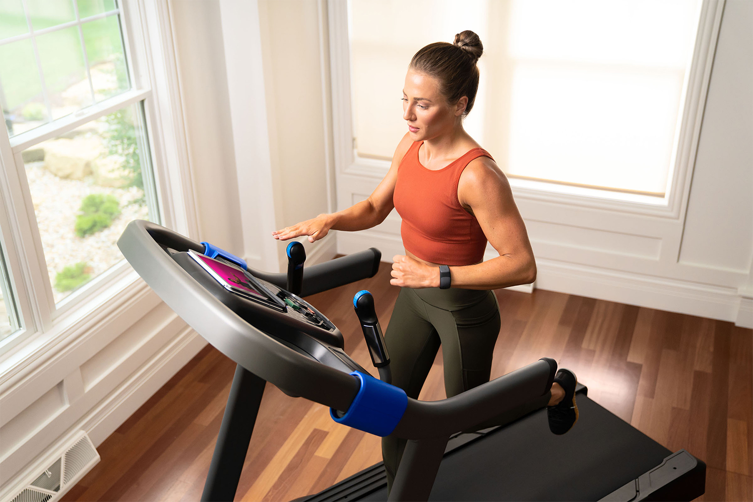 A woman running on the Horizon Fitness 7.0 AT Studio Series treadmill and about to roll the QuickDial controls