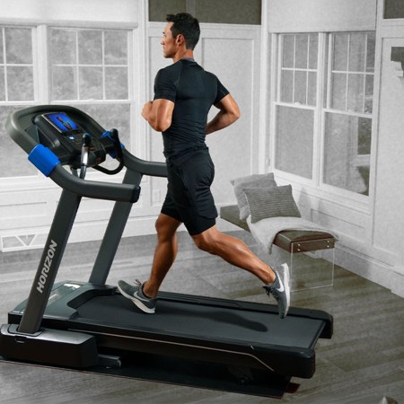 A man running on the Horizon Fitness 7.0 AT Studio Series Treadmill in a house. We tested and reviewed the popular treadmill.