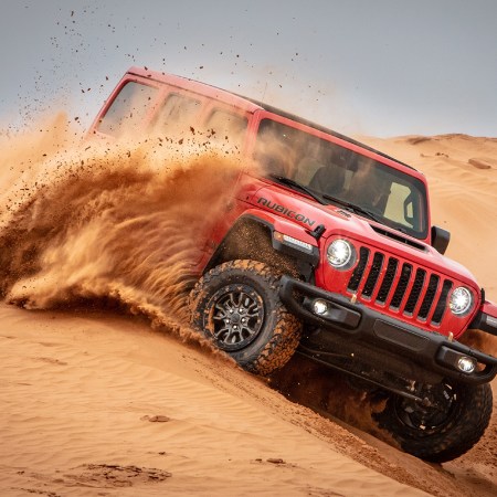 A red Jeep Wrangler Rubicon 392, powered by a V8 engine, driving through sand dunes