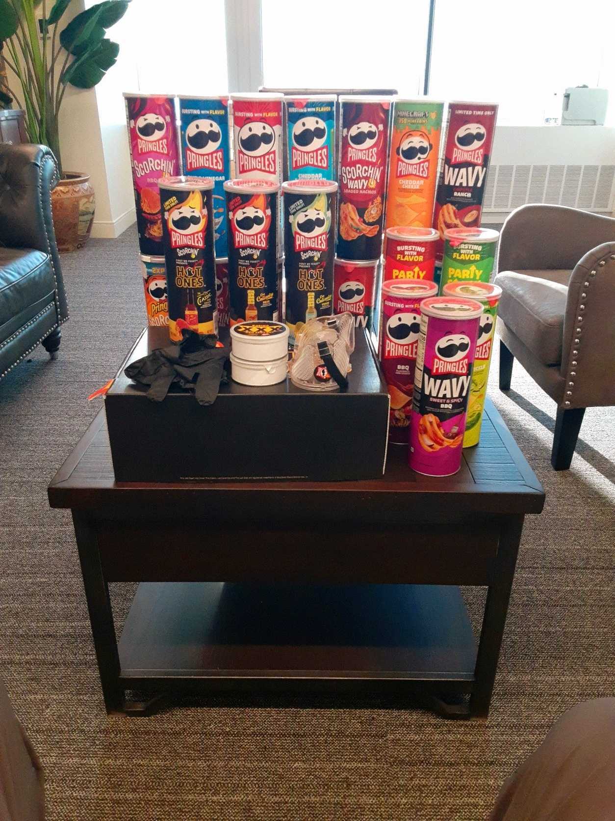 A bunch of cans of Pringles of different flavors on a desk in an office.