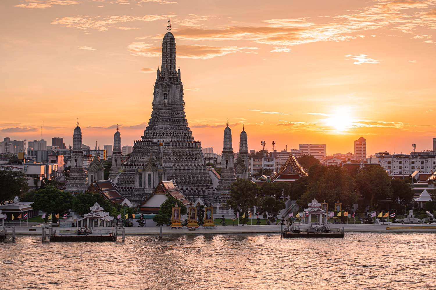 Sunset over Wat Arun Ratchawararam temple on the Chao Phraya river, illuminated by artificial lighting, elevated point of view. Bangkok, Thailand