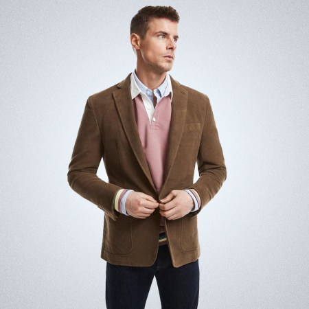 a model in a brown moleskin jacket from Brooks Brothers on a grey background