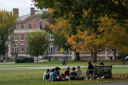 A group of students enjoy class outdoors under a tree on the Dartmouth University campus.